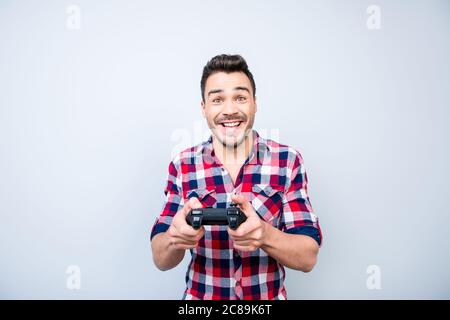 Leben eines einzelnen Mannes.`s Fröhlicher junger Brunet Kerl spielt Spiele drinnen, genießt sich, trägt lässiges Outfit, auf einem hellblauen Hintergrund Stockfoto